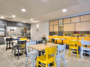 une salle à manger avec des tables et des chaises jaunes dans l'établissement B&B HOTEL Villeneuve Loubet Village, à Villeneuve-Loubet