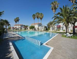a large swimming pool with palm trees in a resort at Mon Repos Hotel in Ayia Napa