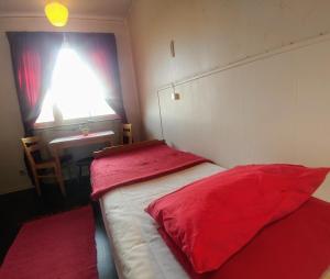 a bedroom with two beds with red sheets and a desk at Storliens Fjällgård in Storlien