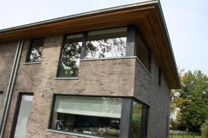 une maison en briques avec une grande fenêtre dans l'établissement TypisGistel, à Gistel