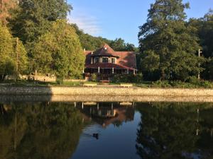 a house sitting on the shore of a lake at Hotel Síkfőkút in Noszvaj