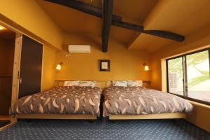 2 Betten in einem Zimmer mit gelben Wänden in der Unterkunft Sakara Miyazu in Miyazu