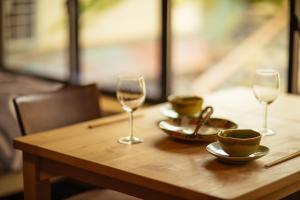 a wooden table with two wine glasses and a bowl at Sakara Miyazu in Miyazu