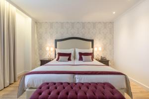 a bedroom with a large bed with a purple ottoman at Luna Hotel Turismo in Abrantes