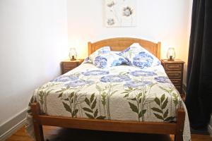 a bed with a blue and white comforter and two night stands at Casa Azul d'Altamira in Viana do Castelo