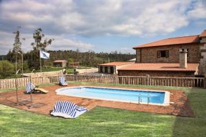 a swimming pool with two chairs in a yard at Casa da Roisa in Rois