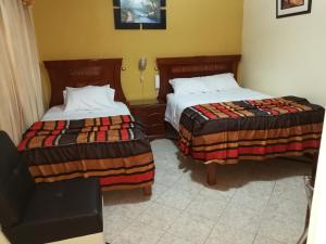 una habitación de hotel con 2 camas y una silla en Hostal El Imperio, en Arequipa
