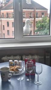 stół z kieliszkami do wina i ptak patrzący przez okno w obiekcie Apartment Kalku 2 w Rydze