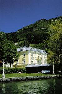 ein großes weißes Gebäude mit einem Dach neben einem Wasserkörper in der Unterkunft Romantik Residenz (Ferienwohnungen Hotel Im Weissen Rössl) - Dependance in St. Wolfgang
