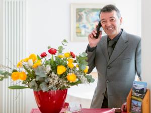 Ein Mann, der auf einem Handy neben einer Blumenvase redet. in der Unterkunft Hotel Oasi in Cortina d'Ampezzo