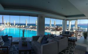 ein Wohnzimmer mit Pool, Sofas und Stühlen in der Unterkunft Meltemi Studios in Megalochori