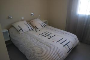 a bed with a white comforter and two pillows at Maison indépendante in Marseille