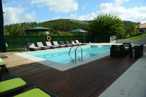 a swimming pool with lounge chairs next to a wooden deck at AboimHouse in Amarante