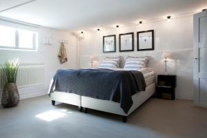biała sypialnia z łóżkiem z niebieskim kocem w obiekcie Wow Apartments Örgryte w Göteborgu