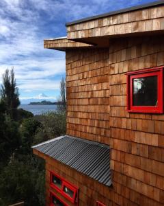 una casa con una finestra rossa sul lato di Almabosque Cabañas a Puerto Varas