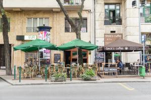 an outdoor cafe with green tables and chairs and umbrellas at Luxury 2BR Apt by the Synagogue in Budapest