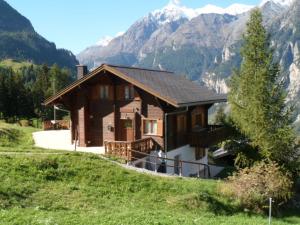 a house on a hill with mountains in the background at Chalet Victoria in Sankt Niklaus