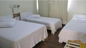 um quarto de hotel com duas camas com lençóis brancos em Hotel Joia em Cascavel