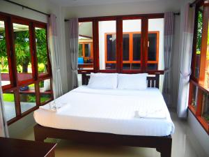 a bedroom with a white bed with windows at Bansuansiriwat in Ban Tak