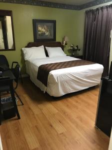 德里平斯普林斯Outpost Motel的卧室配有一张大床和木地板