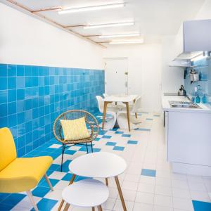une cuisine avec du carrelage bleu, des chaises et des tables jaunes dans l'établissement Superbe appartement sur la plage - Le Zénith, à Palavas-les-Flots