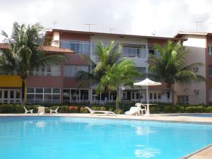 un hotel con piscina con sillas y sombrilla en AP CONFORTAVEL NA PRAIA DO FUTURO FORTALEZA DE 150m 3 QUARTOS 2 SUITES PARA 12 PESSOAS, en Fortaleza