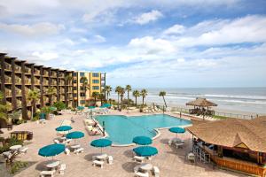 a beach area with chairs, tables and umbrellas at Daytona Beach Hawaiian Inn in Daytona Beach
