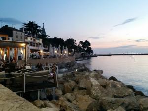 a group of people sitting on the rocks by the water at Leona in Novigrad Istria