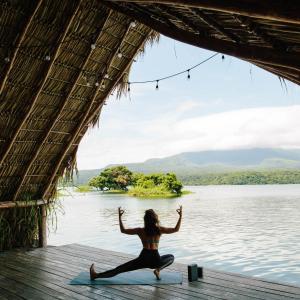 a woman doing yoga on a dock near a body of water at Isleta El Espino in Isletas de Granada