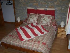 a bed with a red and white blanket and pillows at Le Gîte de l'Ourserie in Méaudre
