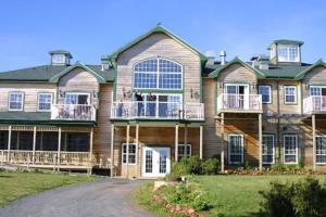 a large house with a porch and a balcony at Ned's Landing at Spry Point in Little Pond