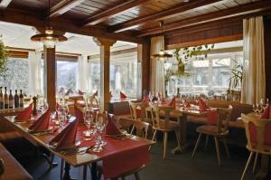 a dining room with tables and chairs and windows at Hotel Arlenwald in Arosa