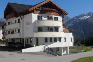 ein großes weißes Gebäude mit einem Holzdach in der Unterkunft Haus Mühlbach in Fiss