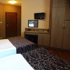 a hotel room with two beds and a flat screen tv at Hotel Šator in Bitola