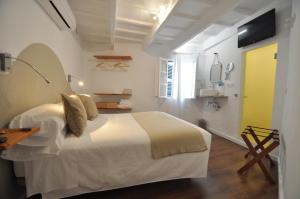 a white bedroom with a bed and a yellow door at Port Antic Ciutadella by My Rooms Hotels TI in Ciutadella