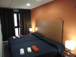 a bedroom with a bed with blue sheets and orange pillows at Studio Loft Fuerteventura in Puerto del Rosario