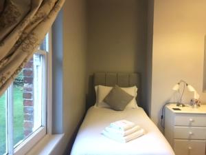 a small bedroom with a bed with a window at Heronshaw House in Hurn