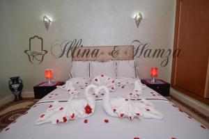 1 dormitorio con 1 cama con 2 cisnes vestidos de blanco en Illina & Hamza Apartment en Marrakech