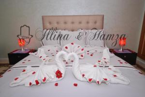 Dos cisnes vestidos de blanco están en una cama en Illina & Hamza Apartment, en Marrakech