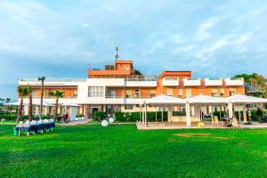 un grande edificio con un prato verde davanti di Sunrise Accessible Resort a Battipaglia