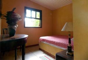 a bedroom with a bed and a table and a window at Pousada Jacu Acu in Petrópolis