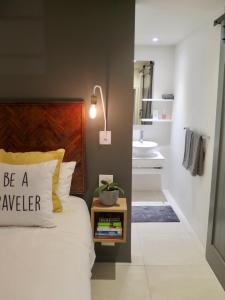 a bedroom with a bed and a bathroom with a sink at Cheviot Place Garden Apartment with Private Entrance in Cape Town