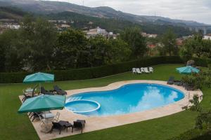 una piscina con sillas y sombrillas en un patio en Hotel Aguiar da Pena, en Vila Pouca de Aguiar