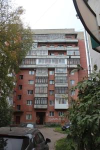 アルハンゲリスクにあるКвартира в центре Воскресенская 75к1の赤レンガの高い建物で、車が目の前に停まっている
