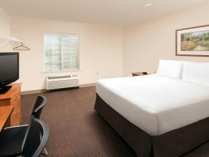 a hotel room with a bed and a flat screen tv at Extended Stay America Select Suites - Salt Lake City - West Valley City in West Valley City