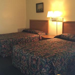 ein Hotelzimmer mit 2 Betten und einer Lampe in der Unterkunft Guest House Motel Chanute in Chanute