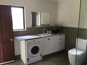 a bathroom with a washing machine and a sink at The Jungle Stays in Millaa Millaa
