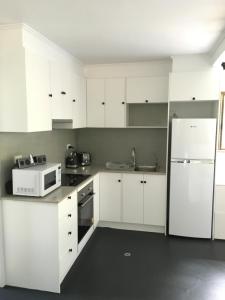 a kitchen with white cabinets and a white refrigerator at The Jungle Stays in Millaa Millaa