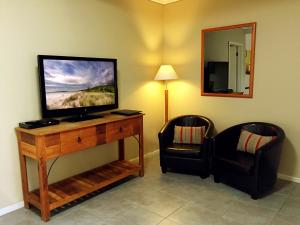 a room with a flat screen tv and a chair at Admiral Motor Inn in Rosebud