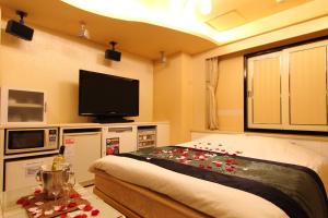 een kamer met een bed en een flatscreen-tv bij Restay Fuchu (Adult Only) in Fuchu